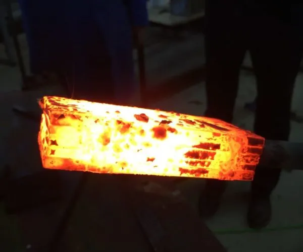 Barre d’acier incandescente à la sortie de la forge